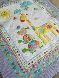 a baby quilt with giraffes and birds on it