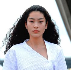 a woman with long dark hair wearing a white shirt