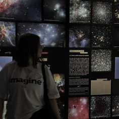 a woman standing in front of a wall full of space images and information on it