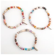 three bracelets made out of different colored beads and some metal scissors on a white surface