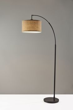 a lamp that is on top of a white table next to a gray wall and floor