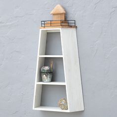 a white shelf with a light house on top and other items in the bottom corner