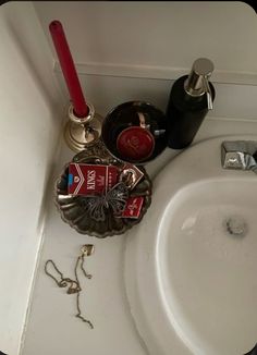 a bathroom sink that has various items on the counter next to it and a red toothbrush