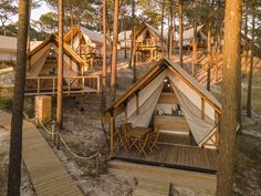 a group of tents in the woods with stairs leading up to them and trees surrounding it