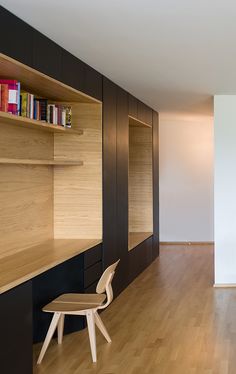 an empty room with wooden floors and bookshelves on the wall, next to a chair