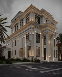 a large white building with lots of windows and palm trees in front of it at night