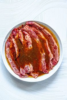 a white bowl filled with meat on top of a table