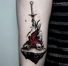 a person with a tattoo on their arm holding a knife and skull in the flame