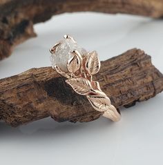 a close up of a ring on top of a piece of driftwood with leaves