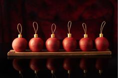 five red apples are lined up on a wooden board with string wrapped around the top