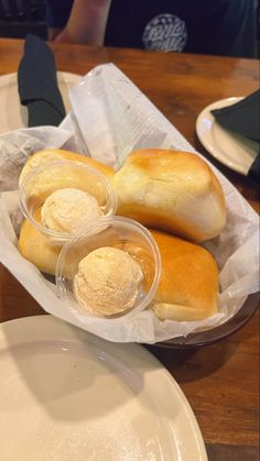 some rolls and ice cream are sitting on a table next to plates with utensils