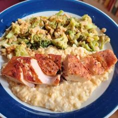 a blue and white plate topped with meat, rice and broccoli covered in sauce