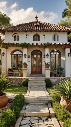 a white house with lots of plants and potted plants on the front porchs