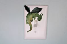 a light switch with a green dragon painted on it's side and an electrical outlet