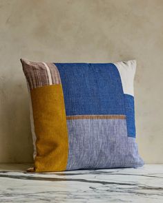 a blue and yellow pillow sitting on top of a marble counter next to a wall