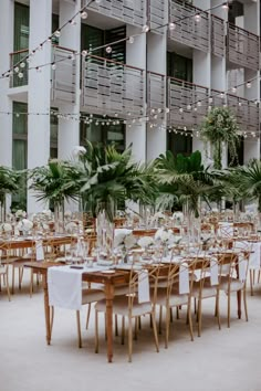 tables and chairs are set up for an event in front of a building with lights strung from the ceiling