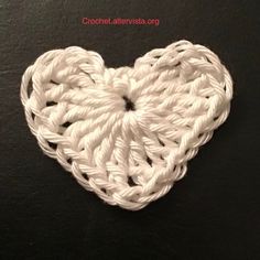 a white crocheted heart on a black surface