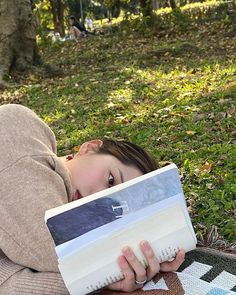 a woman laying on the ground reading a book with her head resting on an open book