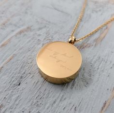 a gold necklace with the word love written on it, sitting on a wooden surface