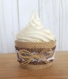 a cupcake covered in white frosting on top of a wooden table