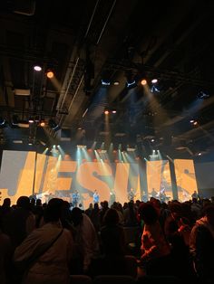 a large group of people sitting in front of a stage with bright lights on it