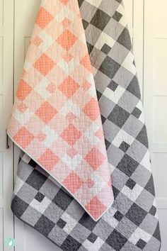 two quilts are hanging on the wall next to each other, one has an orange and gray checkerboard pattern