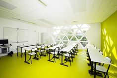 an empty classroom with desks and chairs in front of a whiteboard on the wall