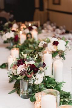 a long table with candles, flowers and greenery is set up for a formal dinner