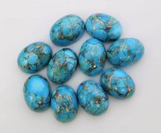 turquoise colored stones are arranged on a white surface