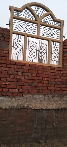 a red brick wall with an iron gate on top and a bird perched on the ledge