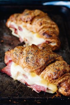 two ham and cheese croissants on a baking sheet, one with melted cheese