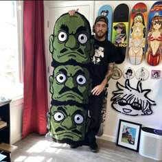 a man standing next to a giant stuffed creature in front of a wall with skateboards on it