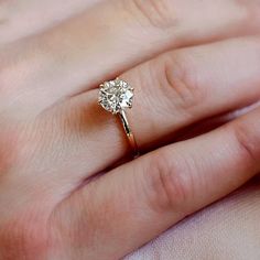 a close up of a person's hand with a diamond ring on their finger