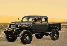 a large green truck parked on top of a sandy beach