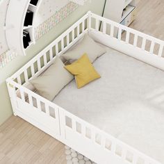 a white crib with two pillows on it and a yellow pillow in the middle