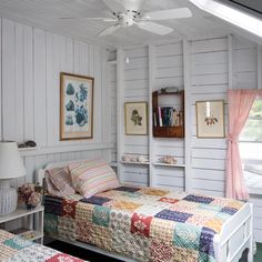 two beds in a room with white walls and green flooring, one has a colorful quilt on the bed