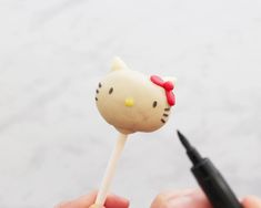 someone holding a hello kitty lollipop with a black marker in front of them