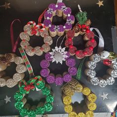 christmas wreaths and other holiday decorations are displayed on a black surface with silver stars