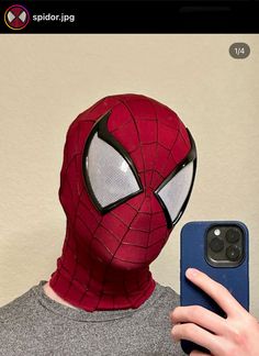 a person wearing a spiderman mask and holding a cell phone