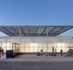 people are standing in front of a building with glass walls and cactuses on the outside