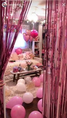 balloons and streamers are hanging from the ceiling in front of a room with pink curtains