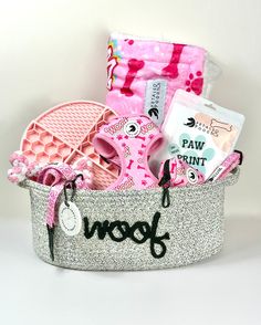 a pink and silver gift basket filled with personal care items on a white table top