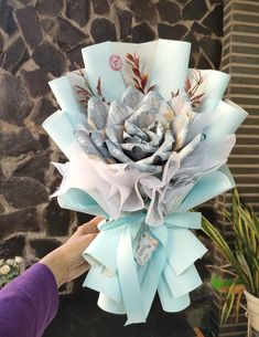 a person is holding up a paper flower