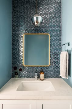 a bathroom with blue and white tiles on the wall, sink and mirror in it