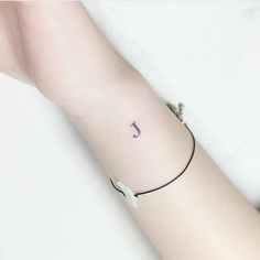 a woman's arm with a small initial tattoo on the left side of her arm