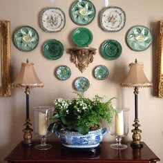 a table topped with lots of plates and vases next to two lamps on either side of it