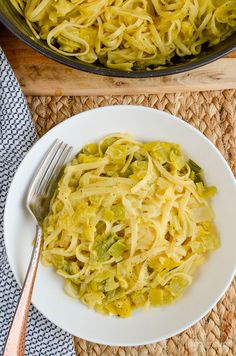 a white plate topped with pasta next to a skillet