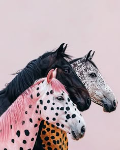 three different colored horses standing next to each other on a pink background with black and white spots