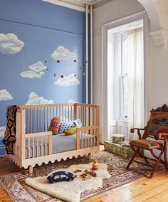 a baby's room with a crib, rocking chair and wall mural in the background