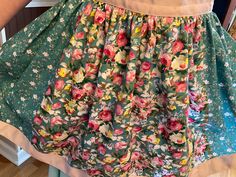 a woman is wearing a skirt with flowers on it and has her hands in the pockets